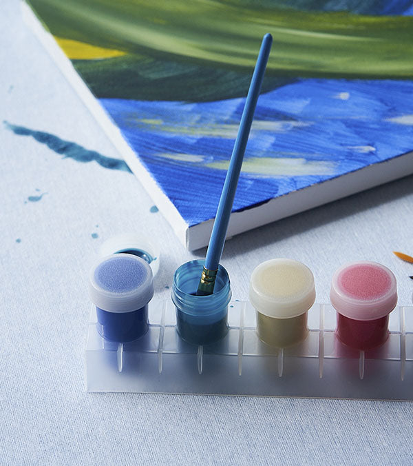 a canvas and acrylic paints sit on top of a surface protected by Katch protective surface roll