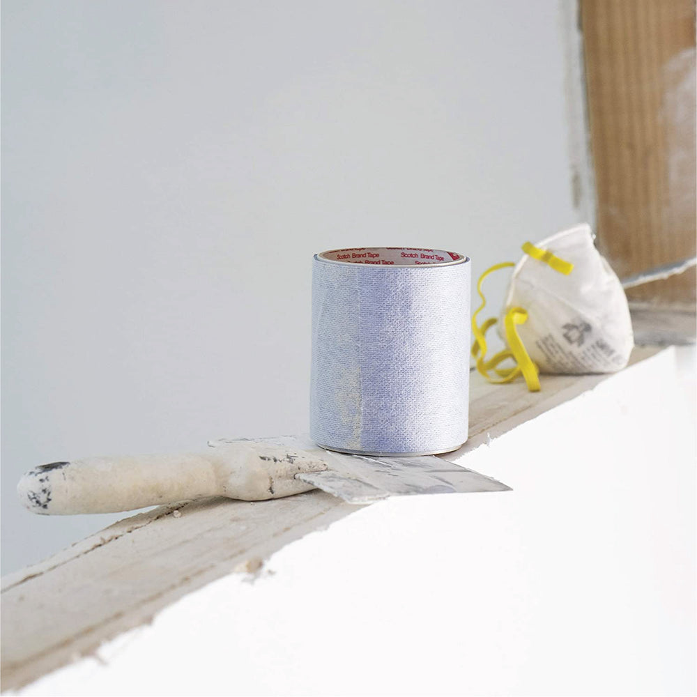 a paint scraper and a painters mask sit on a ledge next to a roll of Katch painters tape